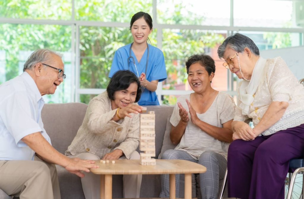 a group of seniors playing jenga  while their caregiver watching them in memory care community.