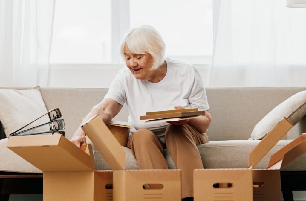 Senior sorting household items into moving boxes while downsizing her home.