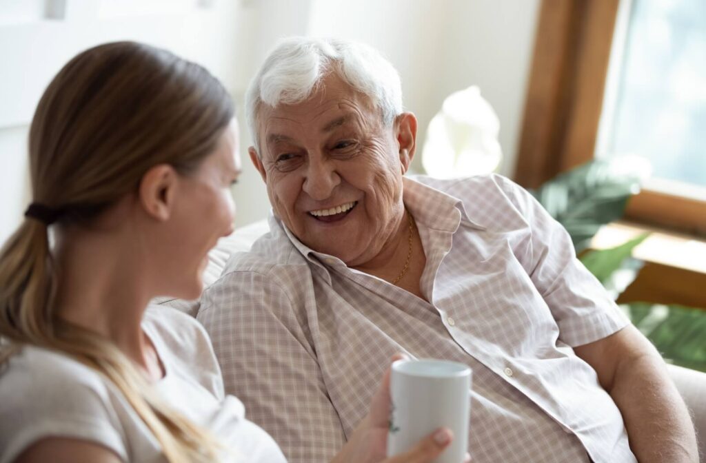 An older adult laughing in memory care during a visit with their adult child.