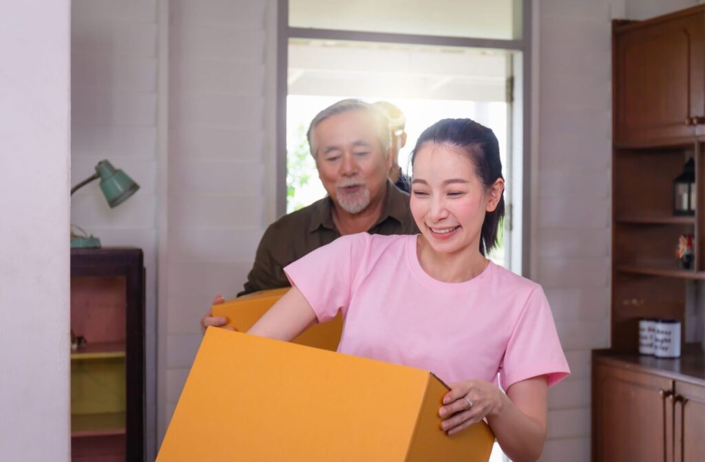 An adult child helps their older parent move boxes into their new apartment in a memory care home