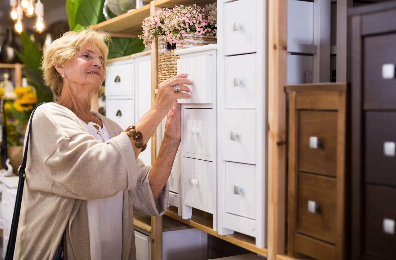 A senior browsing drawers and stands at a furniture store shopping for her new home in senior living