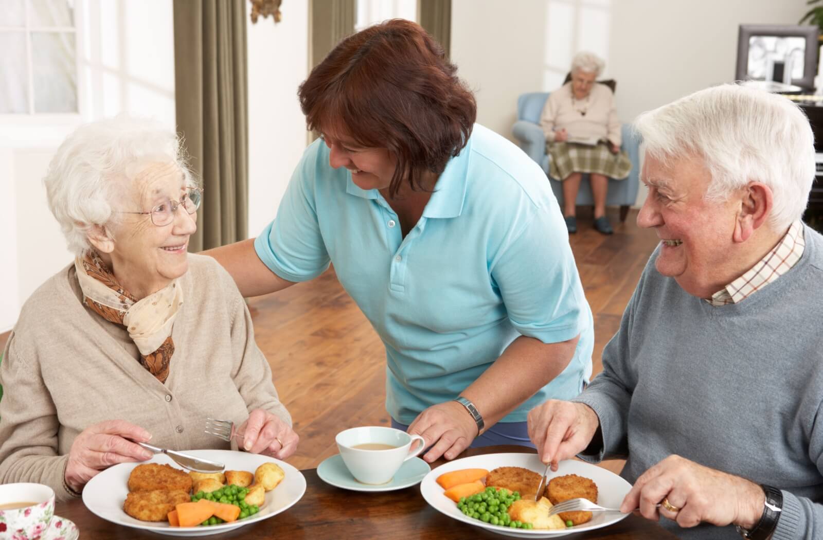 caregiver checking on a senior while dining in memory care